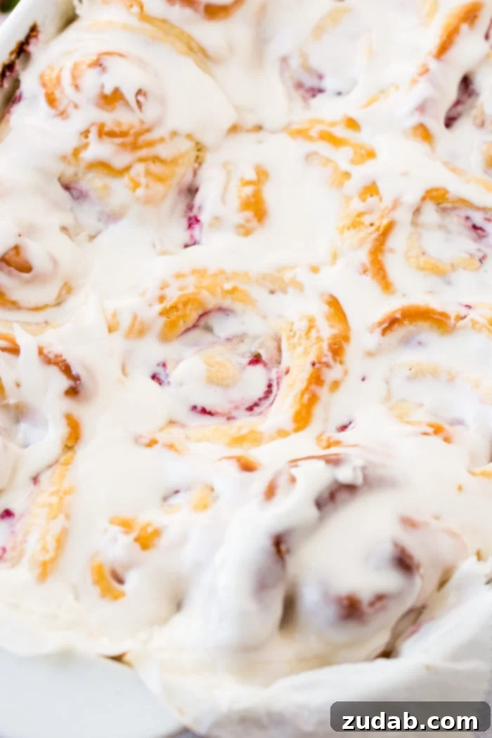 Effortless Raspberry Sweet Rolls 3 A photo of a pan of easy raspberry sweet rolls covered in frosting.