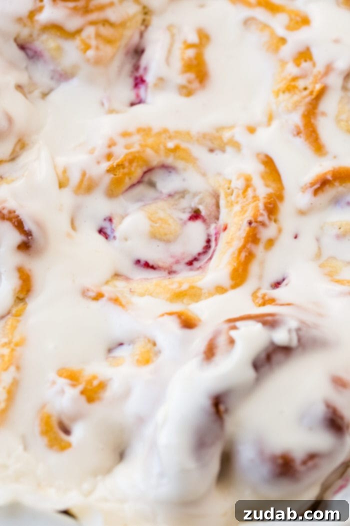 Effortless Raspberry Sweet Rolls 6 A photo of a pan of easy raspberry sweet rolls covered in frosting.