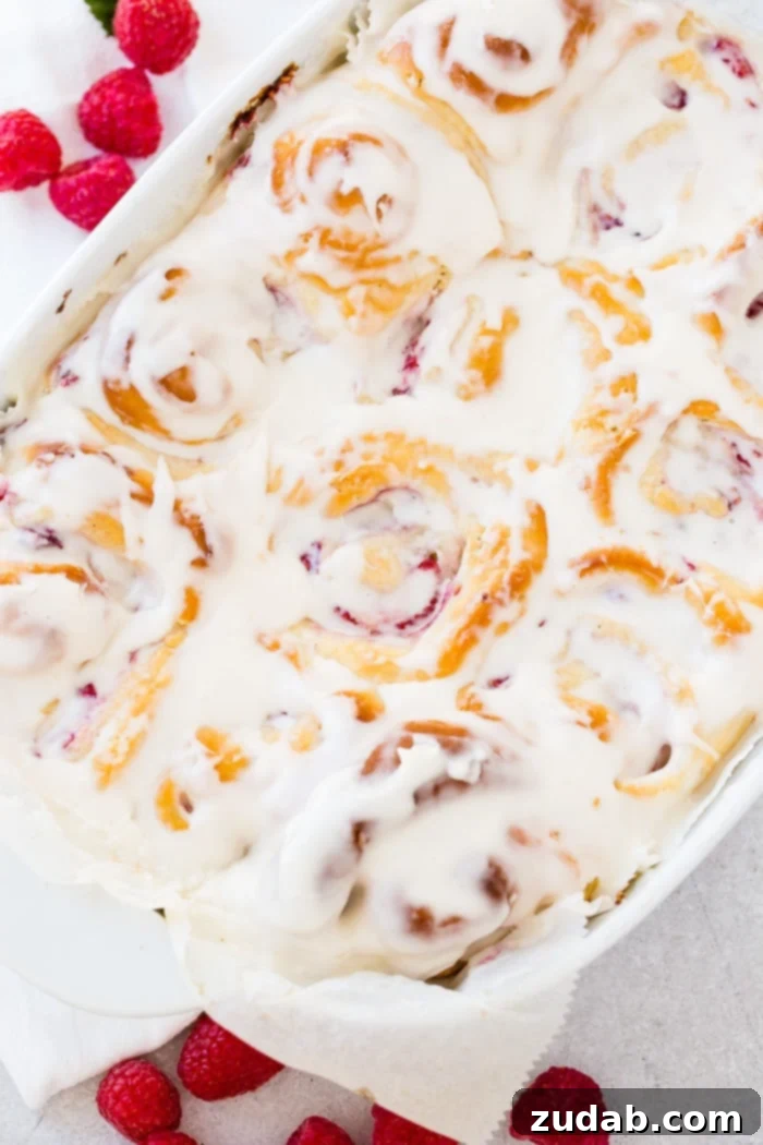Effortless Raspberry Sweet Rolls 7 A photo of a pan of easy berry sweet rolls covered in frosting.
