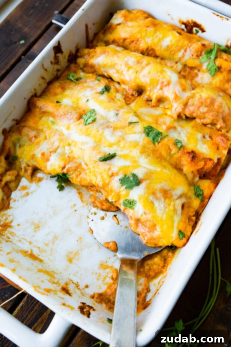 Seriously Simple Bean and Cheese Enchiladas 4 A photo of a baking dish of baked bean and cheese enchiladas with a couple of enchiladas removed, showing the cheesy layers.