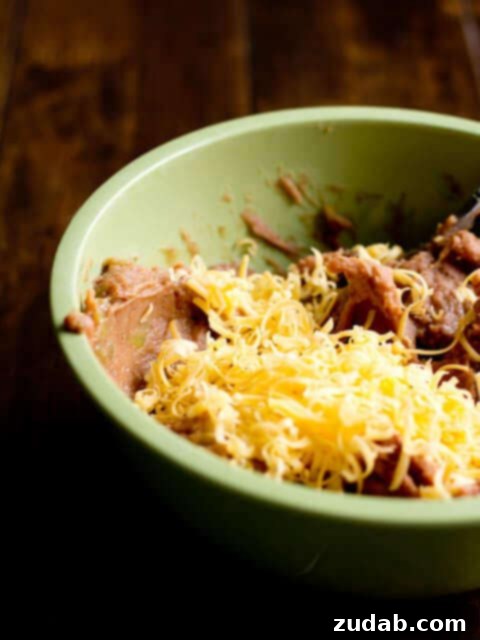 Bean and cheese smothered enchiladas ohsweetbasil.com Freshly baked bean and cheese enchiladas in a baking dish, with a serving spoon.