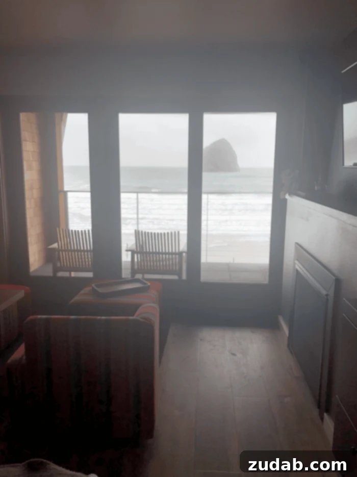 Road Trip Ready Snacks and Entertainment Solutions 8 A stunning photograph captured from a hotel room, showcasing the iconic Cannon Beach in Oregon framed perfectly within the window. On the inviting patio, two chairs are strategically placed, offering an unparalleled view of the vast ocean and the majestic Haystack Rock, creating a serene coastal retreat.