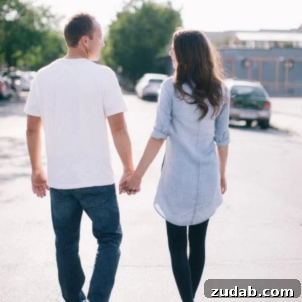 A photo of Cade and Carrian holding hands from behind, walking, and looking at each other.