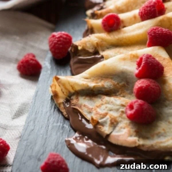 Through the Gloom: Faith's Enduring Struggle Part 19 4 A delectable close-up photo of freshly made crepes, generously filled with rich Nutella and adorned with vibrant, ripe raspberries and sliced bananas, presented beautifully on a plate.