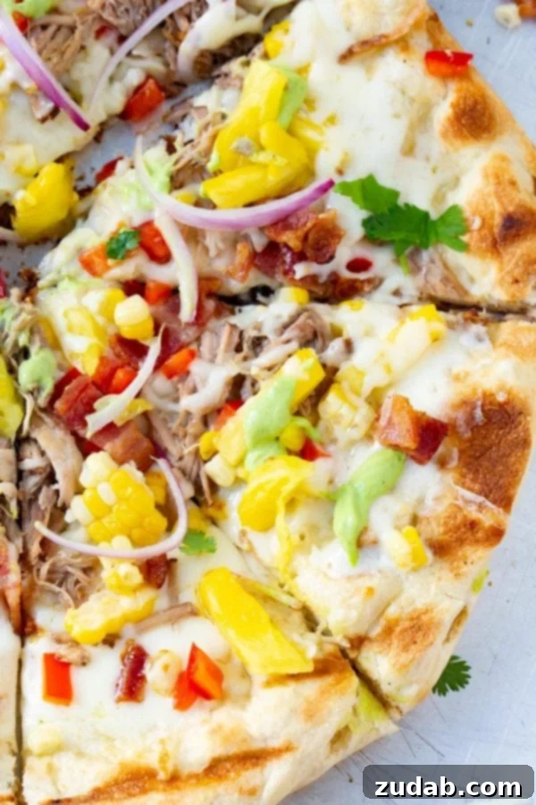Pulled Pork Pizza with Sweet Corn and Cilantro Cream A photo of pulled pork pizza covered in sweet corn, red onions, pinapple, bacon, and fresh cilantro.