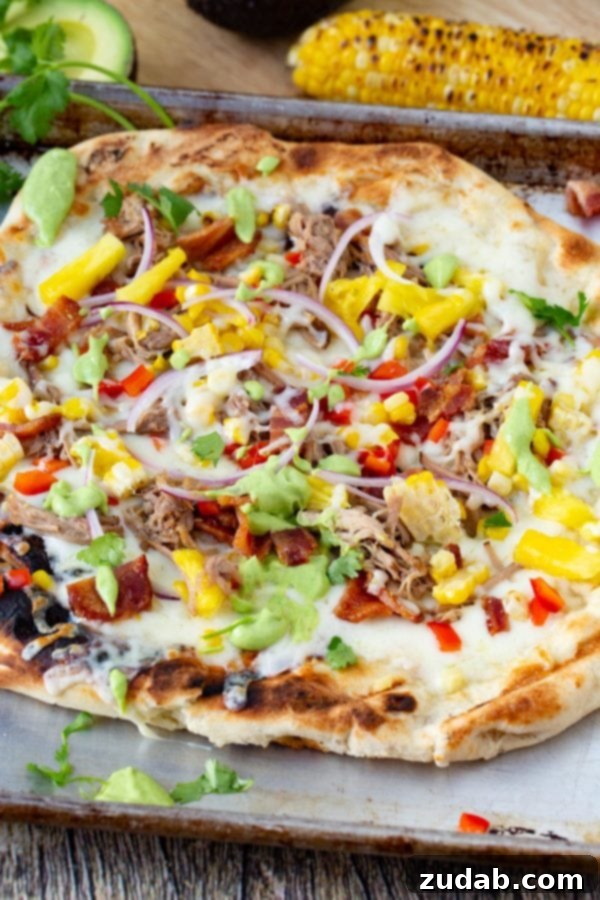 Pulled Pork Pizza with Sweet Corn and Cilantro Cream A photo of pulled pork pizza covered in sweet corn, red onions, pinapple, bacon, and fresh cilantro.