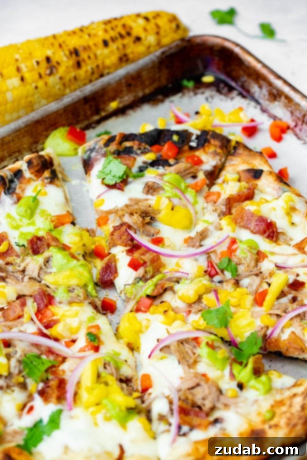 Pulled Pork Pizza with Sweet Corn and Cilantro Cream A photo of pulled pork pizza covered in sweet corn, red onions, pinapple, bacon, and fresh cilantro.
