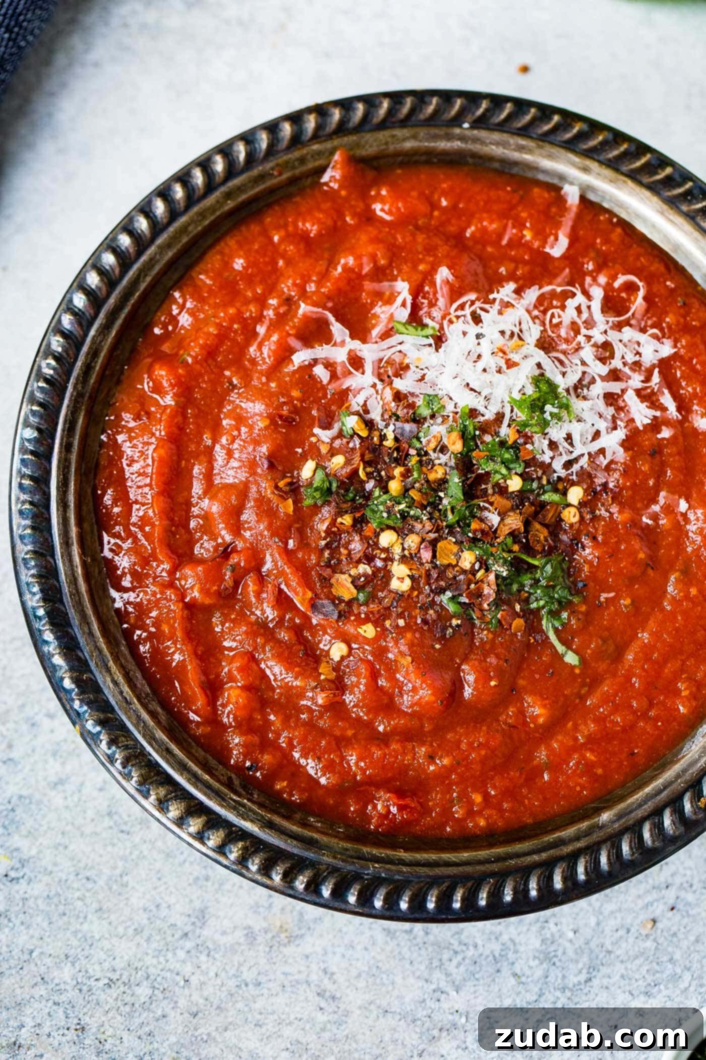 The Simplest Homemade Pizza Sauce You'll Ever Make 2 A black bowl of pizza sauce. The sauce is sprinkled with cheese and herbs.