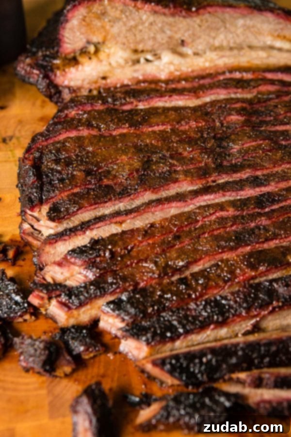 Perfectly Smoked Brisket Recipe A photo of perfectly smoked brisket sliced on a wooden cutting board.