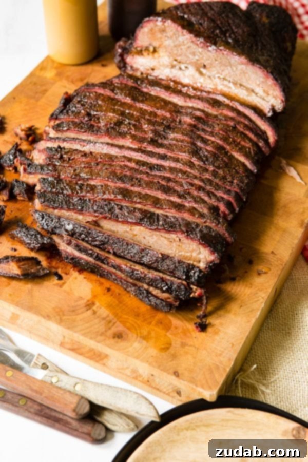 Perfect Smoked Brisket Recipe A photo of perfectly smoked brisket sliced on a wooden cutting board.