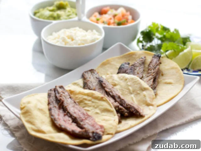 Marinated flank steak on three corn tortillas with three white bowls of authentic carne asada tacos ingredients. 