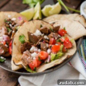 Two authentic carne asada tacos on a serving plate on top of a wooden table.