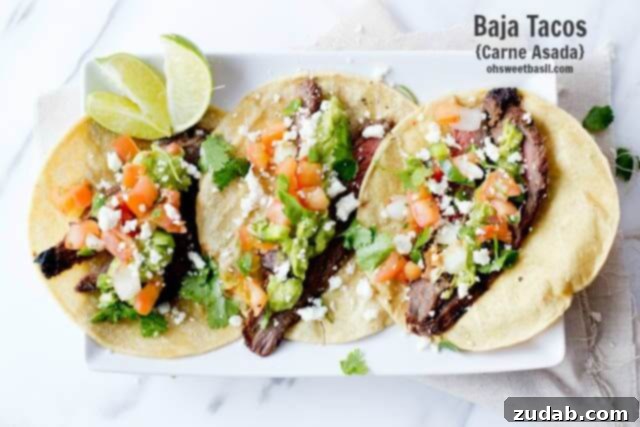 Three authentic carne asada tacos with three slices of lime on a white serving platter.