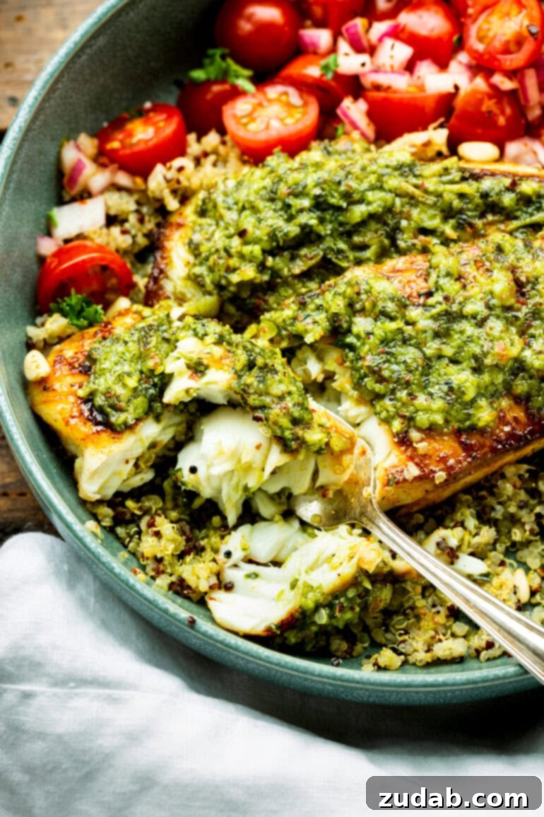 Pesto Tilapia Easy Low Calorie Dinner Video 3 a photo of a fork cutting into a flaky filet of tilapia topped with bright green pesto sauce