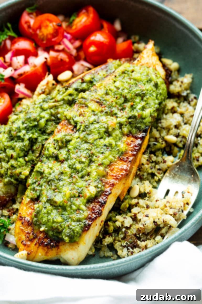 Pesto Tilapia Easy Low Calorie Dinner Video 6 a photo of two golden seared tilapia filets topped with pesto and served on top of multicolored tilapia.
