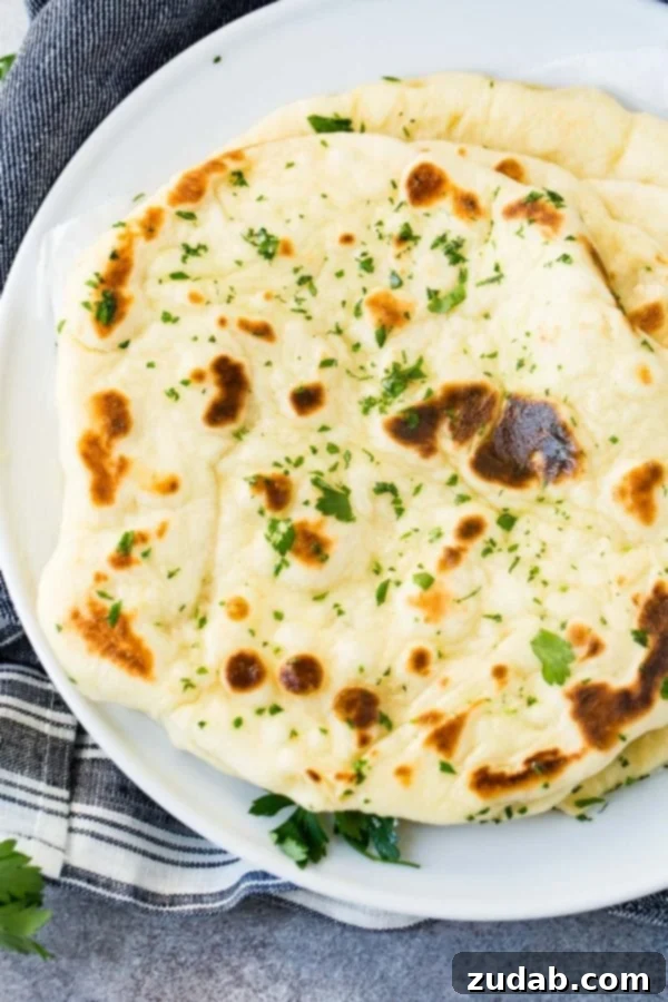Easy Homemade Naan Recipe A close-up shot of a single piece of homemade naan, garnished with fresh cilantro, highlighting its fluffy texture.