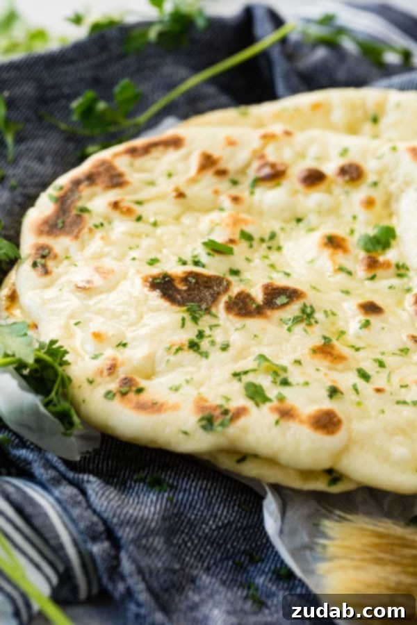 Easy Homemade Naan Recipe A perfectly cooked piece of naan bread, golden-brown and slightly charred, showcasing its delicious texture.
