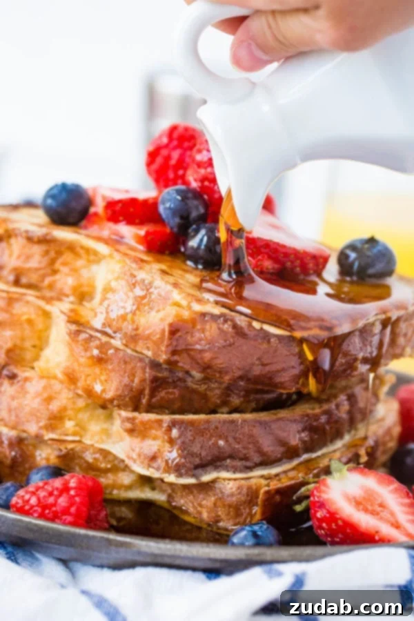 How to Make French Toast A photo of syrup being poured over a stack of french toast covered in fresh berries.