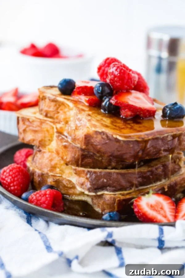 How to Make French Toast A photo of french toast with a stack of french toast covered in dripping syrup and fresh berries.