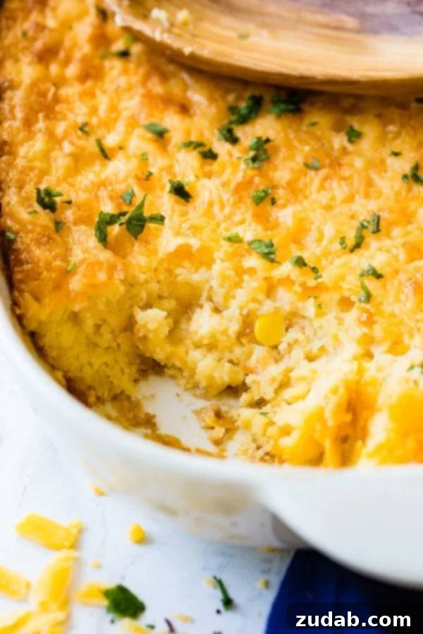 Cheesy Jiffy Cornbread Casserole A photo of a baking dish full of cornbread casserole with a serving removed.