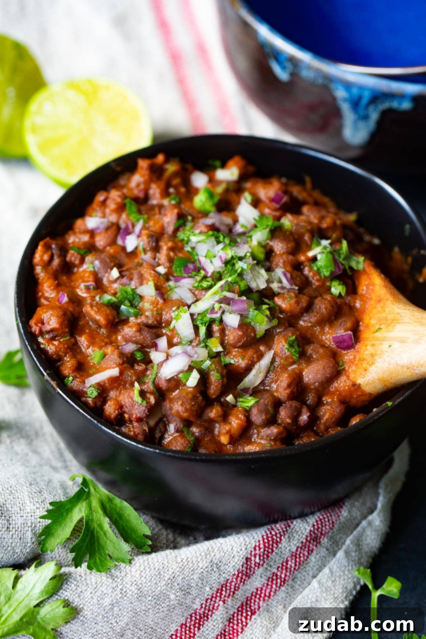 The Most Delicious Mexican Black Beans Ever A bowl of savory Mexican black beans, topped with vibrant red onion and fresh cilantro, waiting to be enjoyed. The textures are rich and inviting.