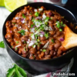 A close-up of a bowl of delicious Mexican black beans garnished with fresh cilantro, ready to be served as a vibrant side dish.