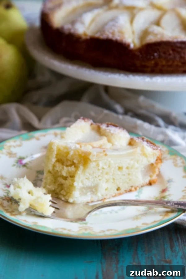 Classic Italian Pear Almond Cake 2 A beautifully presented slice of Italian pear cake on a plate, garnished lightly with powdered sugar, ready to be enjoyed.