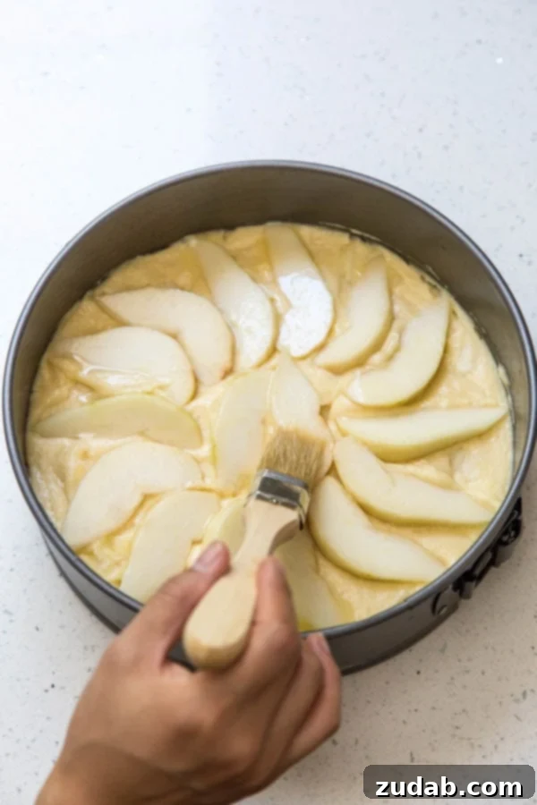 Classic Italian Pear Almond Cake 4 Close-up shot of pear slices being brushed with melted butter before baking, ready for the oven.
