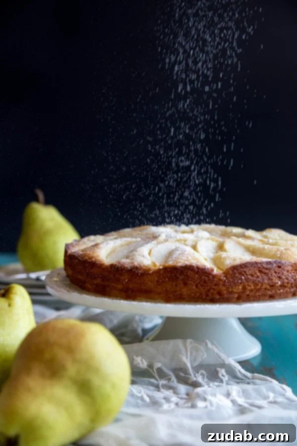 Classic Italian Pear Almond Cake 5 A finished Italian pear cake being dusted with a fine layer of powdered sugar for a beautiful presentation.