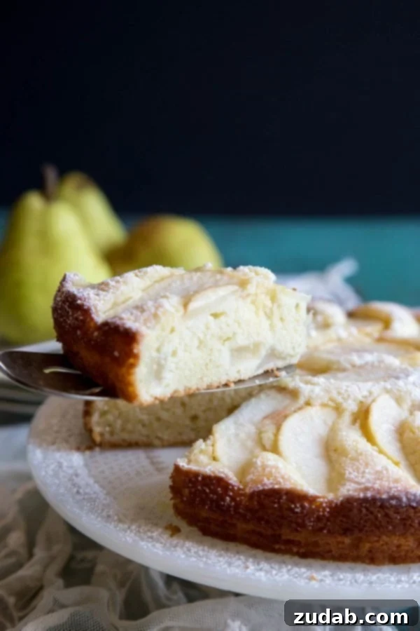 Classic Italian Pear Almond Cake 6 A slice of warm Italian pear cake being served on a rustic plate, highlighting its tender crumb and pear topping.
