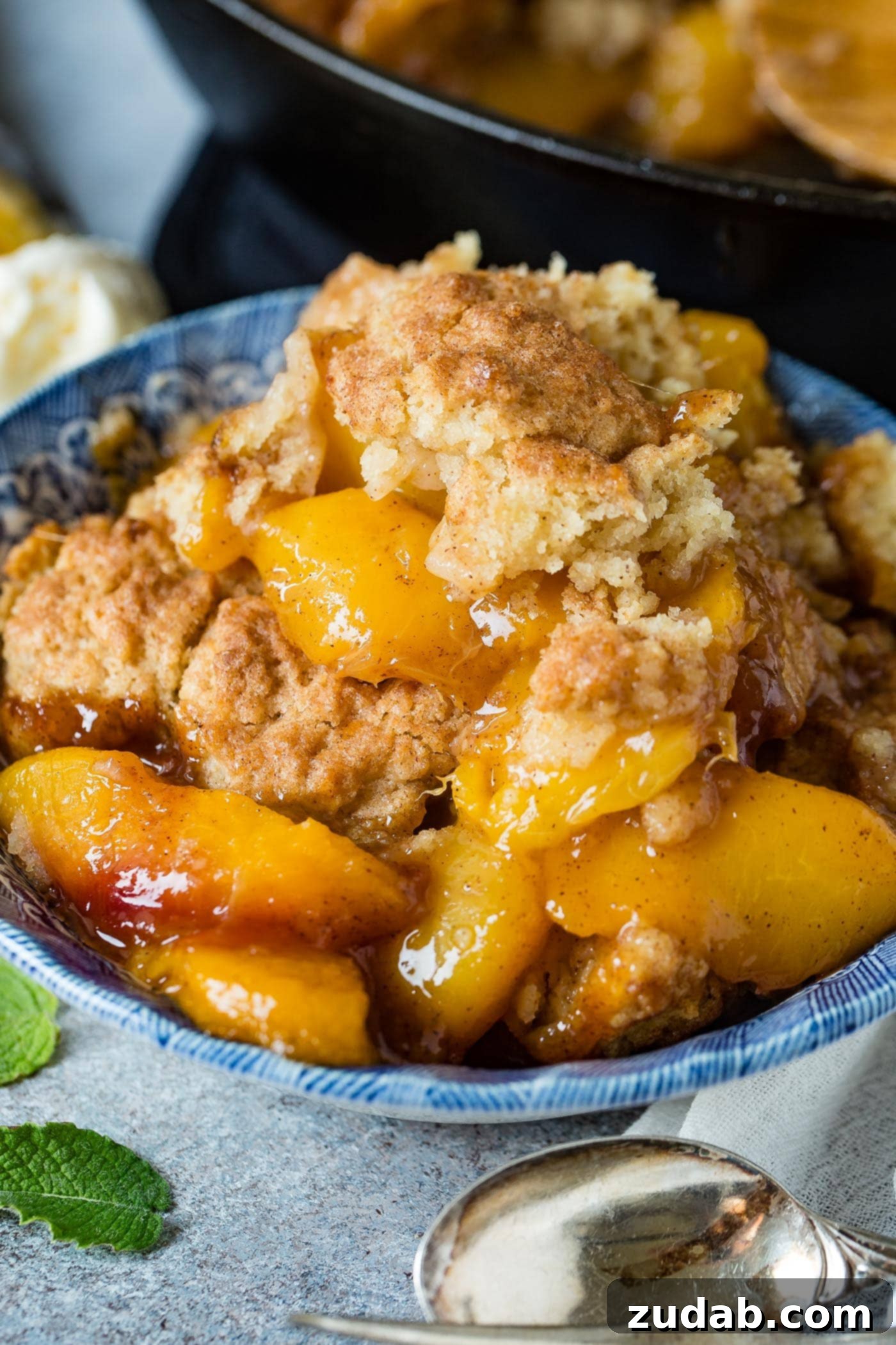 A photo of a bowl of peach cobbler with a biscuit topping.