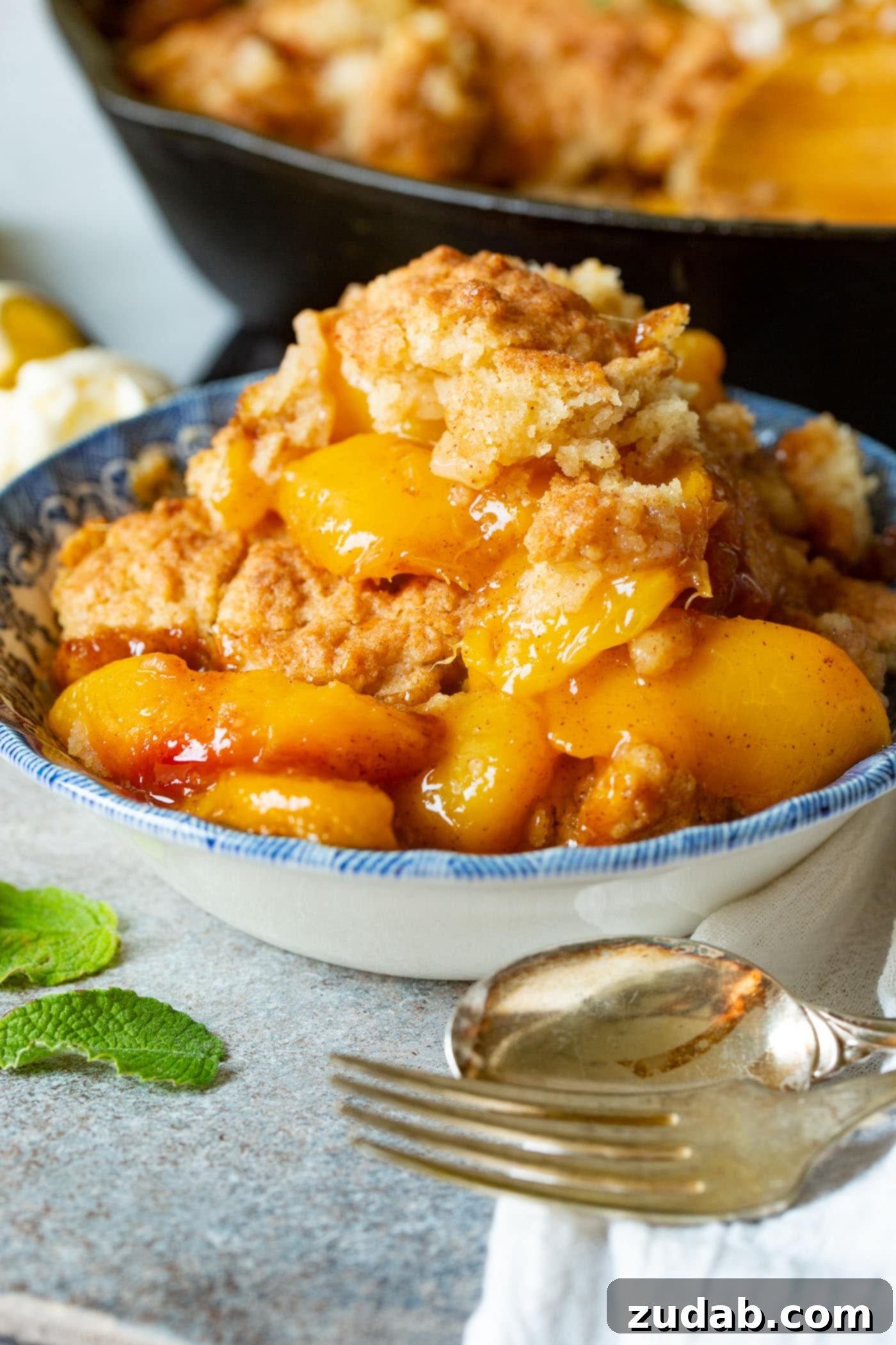 A photo of a bowl of peach cobbler with a biscuit topping.