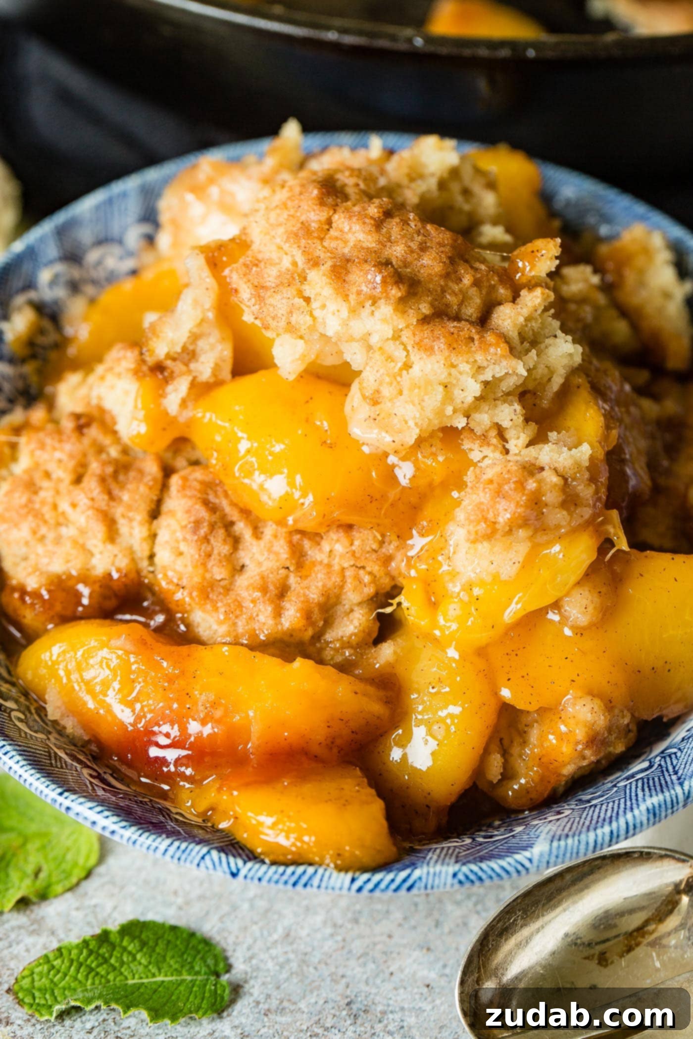 A photo of a bowl of peach cobbler with a biscuit topping.