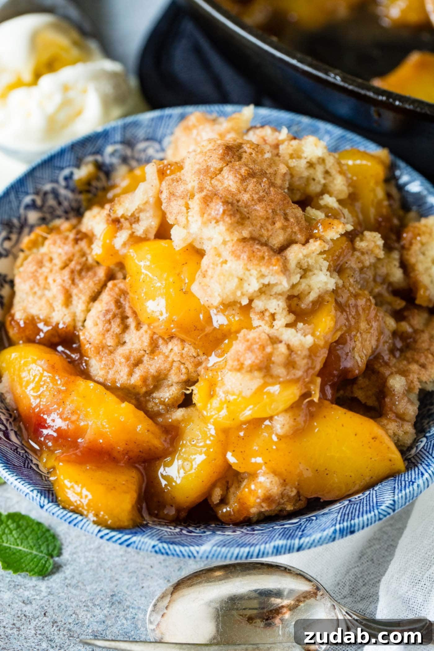 A photo of a bowl of peach cobbler with a biscuit topping.