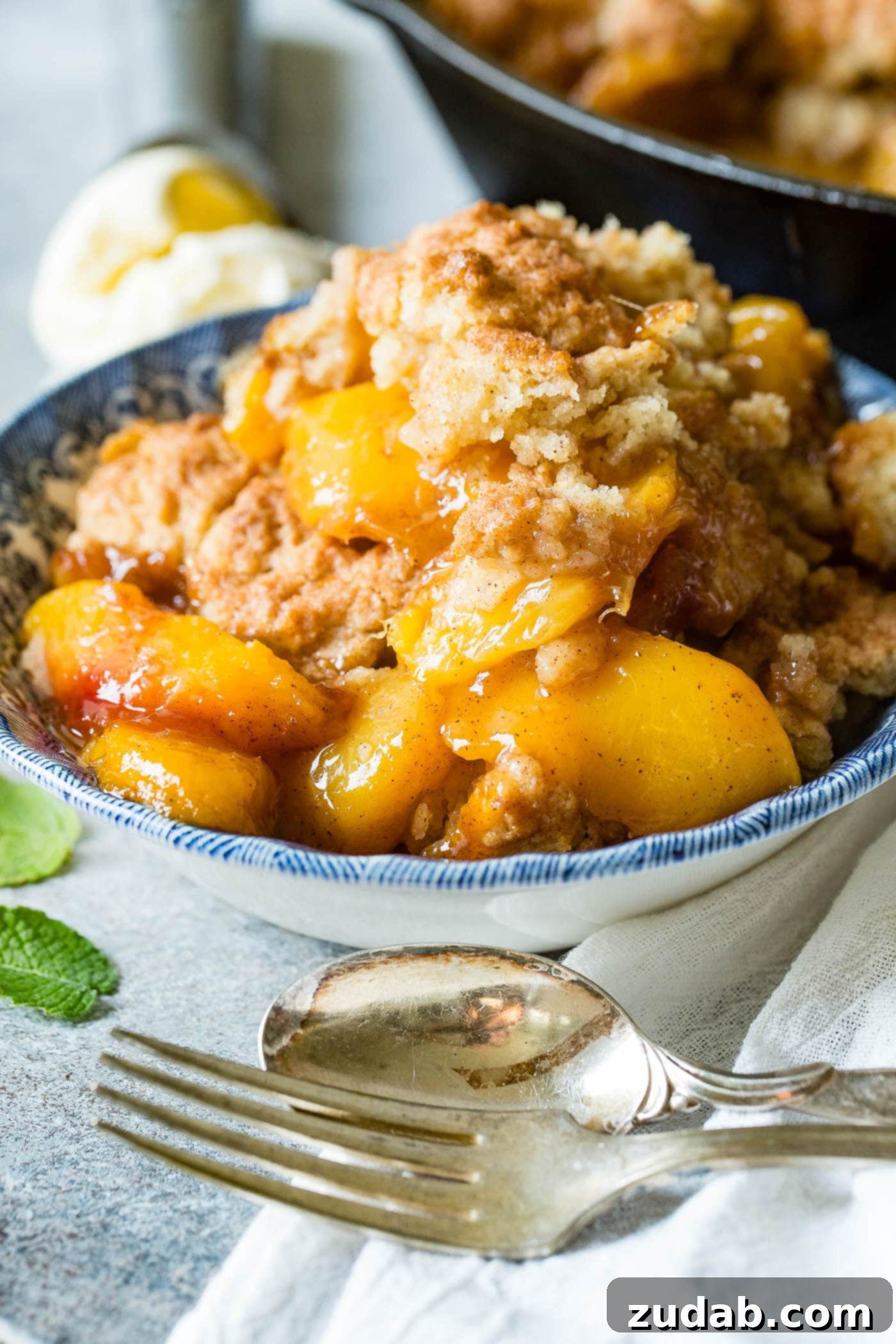 A photo of a bowl of peach cobbler with a biscuit topping.