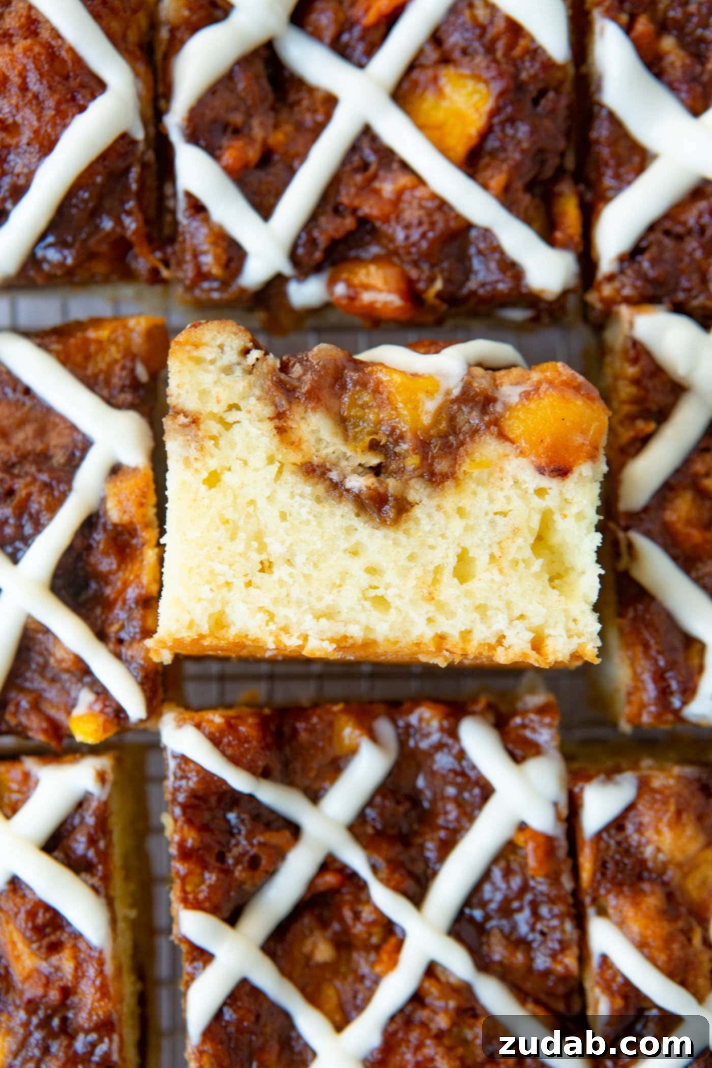 Easy Peach Sour Cream Coffee Cake An overhead shot showcasing several inviting pieces of peach coffee cake, with one slice tilted to reveal its moist interior and luscious peach swirl, highlighting its homemade appeal.