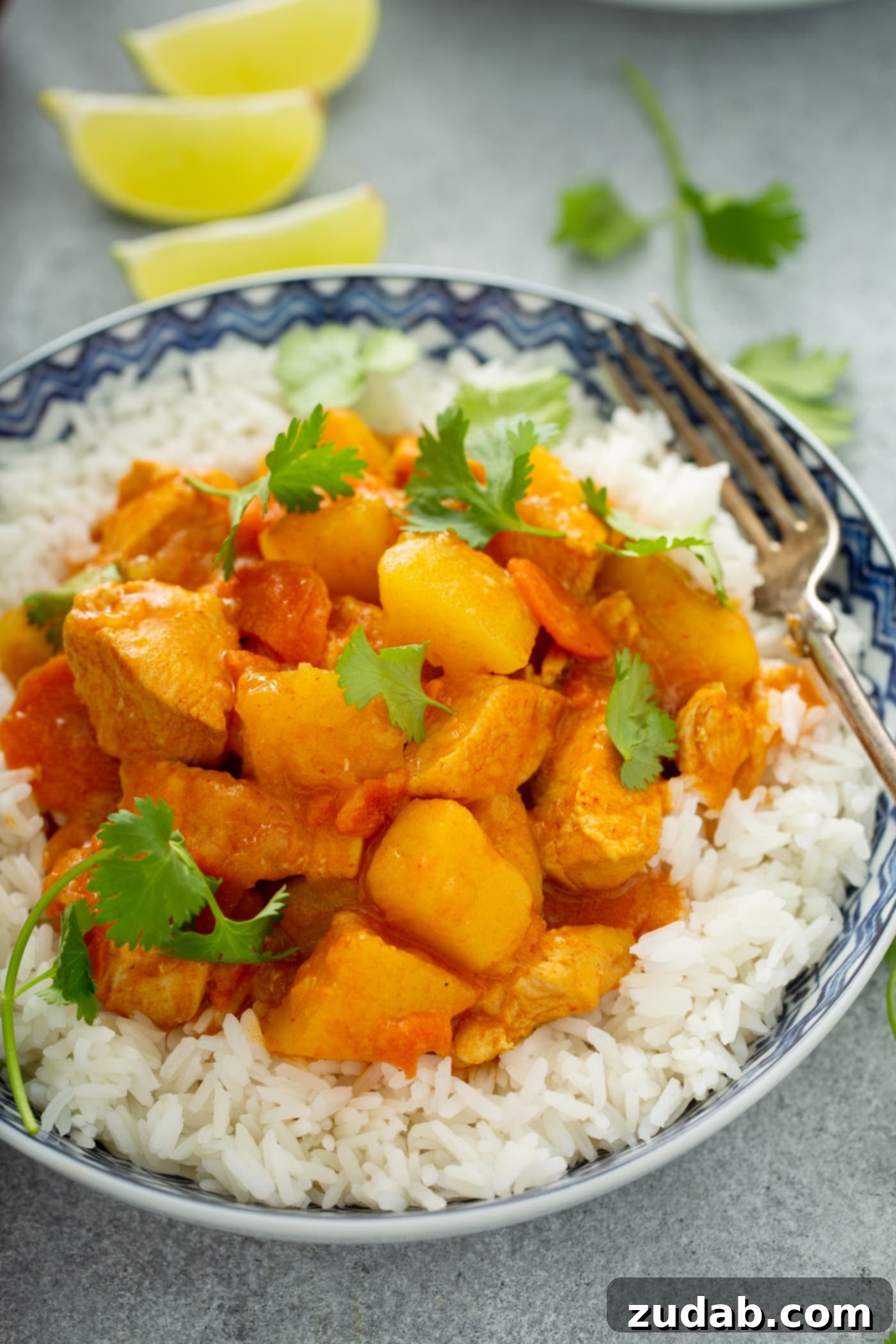 Chicken Curry Recipe in the Instant Pot A bowl of white rice with chicken curry on top. there are chunks of chicken, carrots, and potatoes in a curry sauce. The curry is sprinkled with fresh parsley.