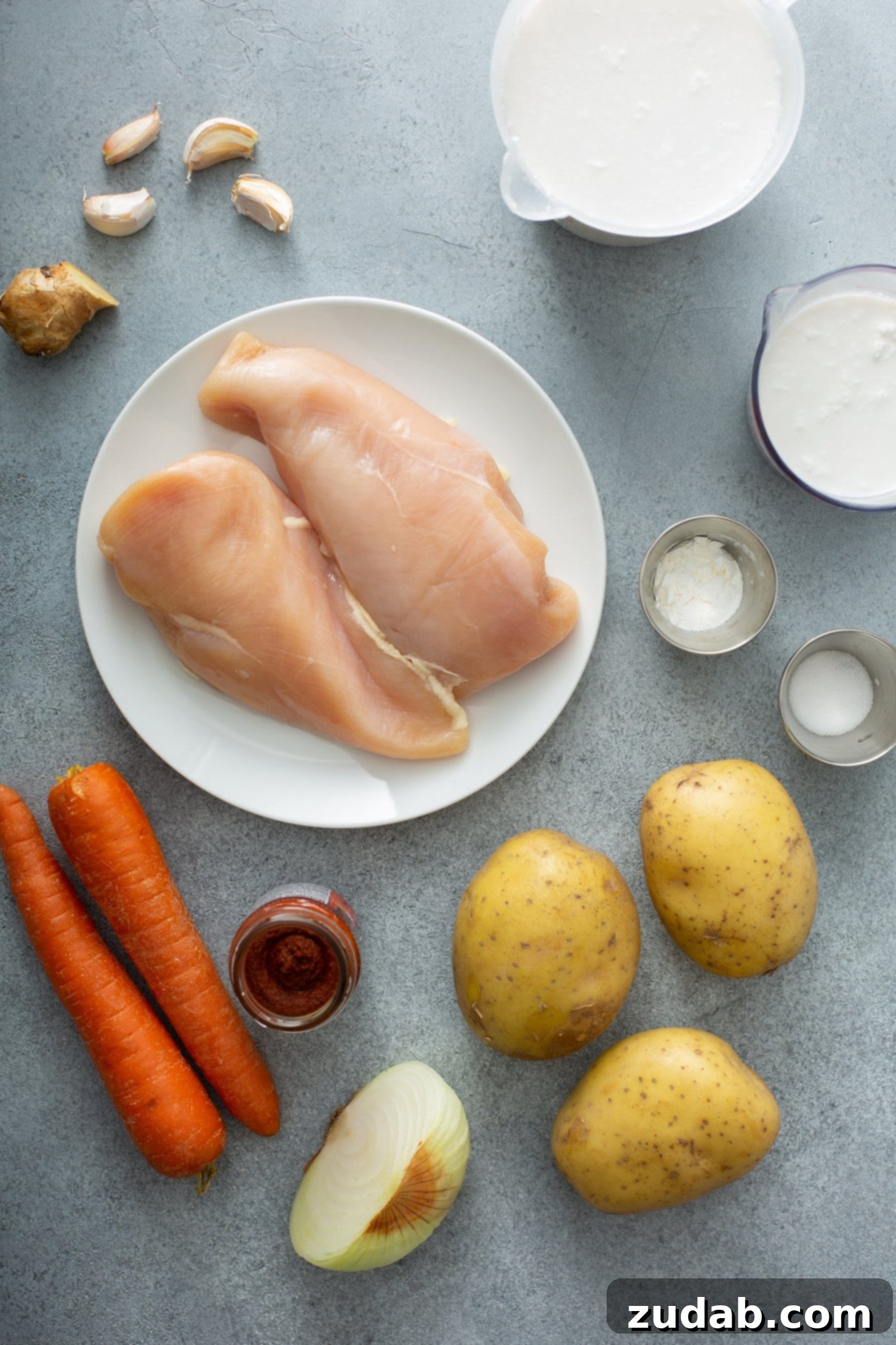Chicken Curry Recipe in the Instant Pot Ingredients for chicken curry. There are three peeled potatoes, two carrots, two chicken breasts, and curry paste, garlic, onion, cream, and salt.