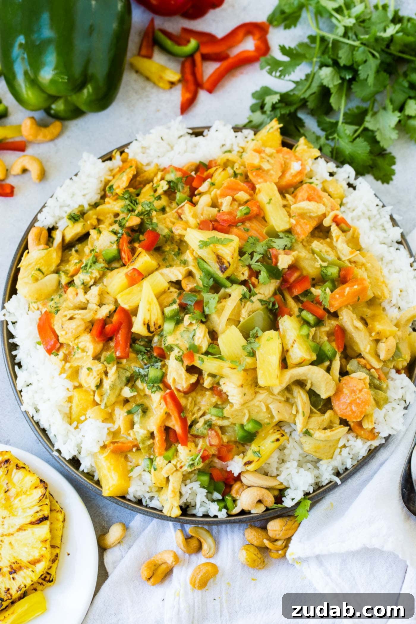 Golden Island Pineapple Coconut Chicken Curry 5 a plate with jasmine white rice piled with a creamy pineapple coconut curry sauce, peppers, onions and cashews with grilled pineapple