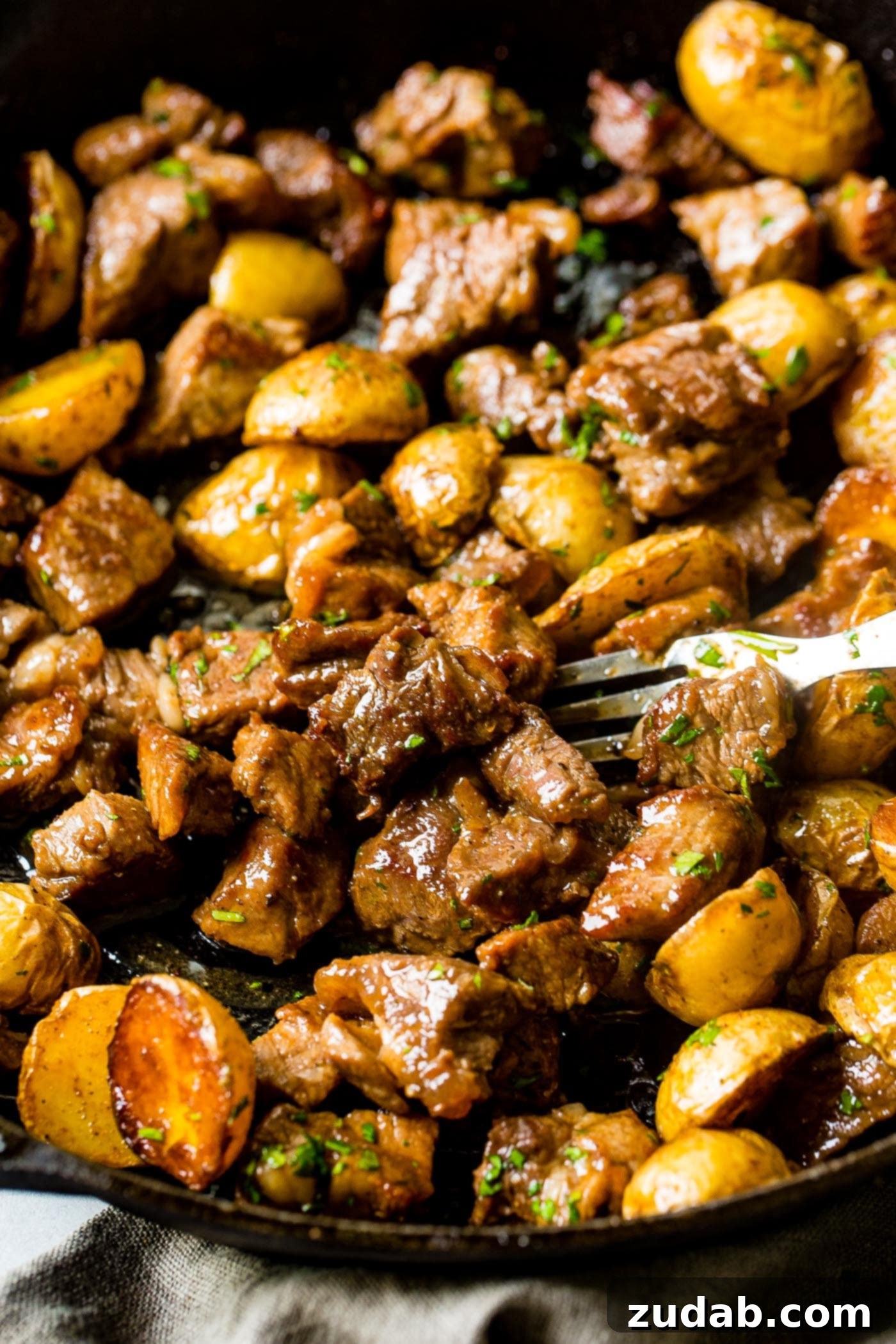 One Skillet Smoky Steak and Potatoes A photo of a cast iron skillet full of golden halved potatoes and beautifully seared steak, ready to serve.