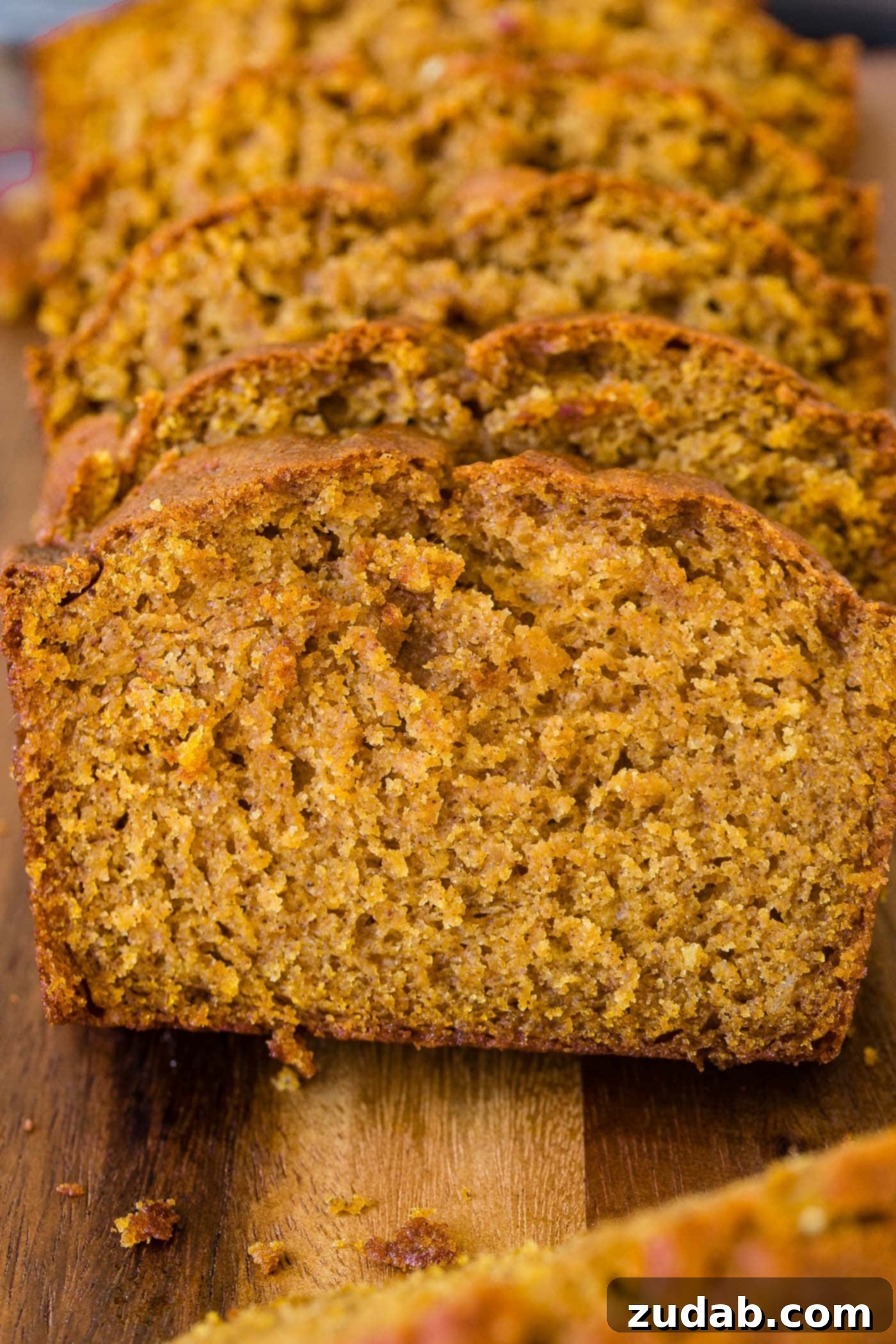 Perfect Pumpkin Bread for Fall A freshly baked and sliced loaf of pumpkin bread displayed on a wooden board, emphasizing its enticing texture.