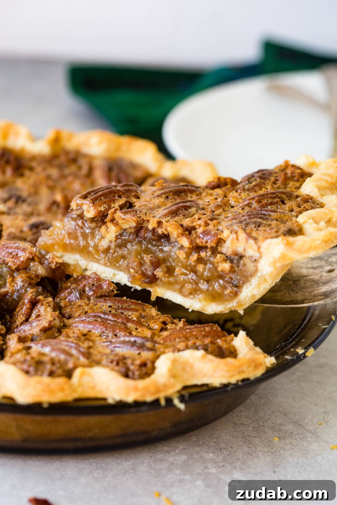 A photo of a slice of pecan pie being removed from a whole pie.