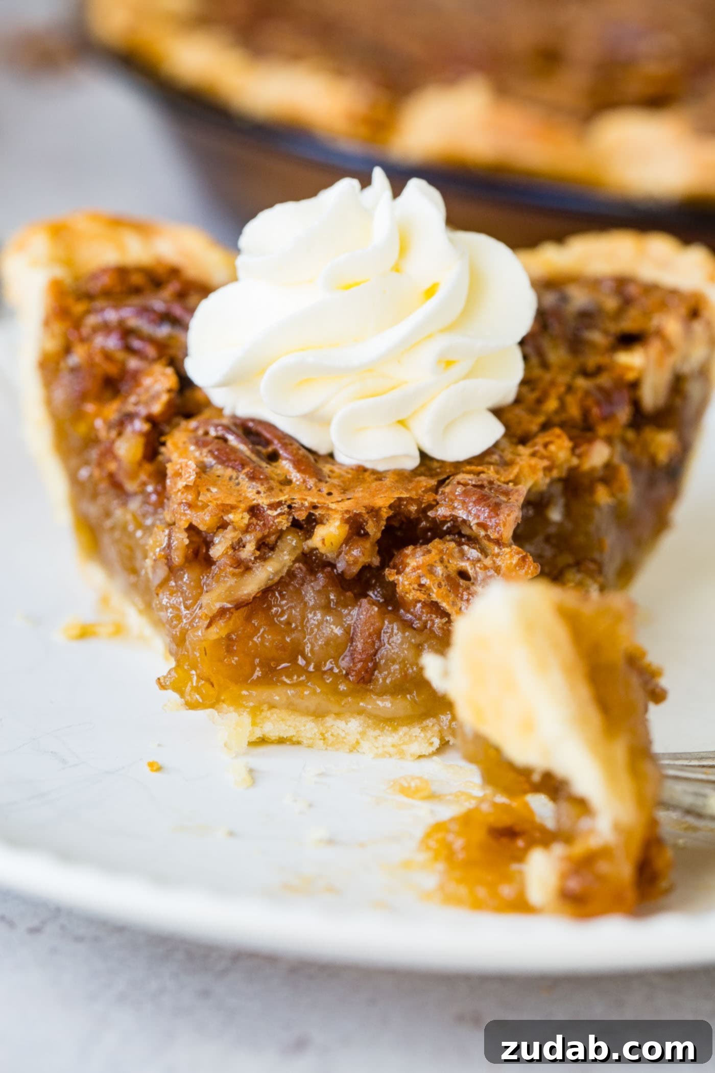 A photo of a slice of pecan pie with a bite taken out.