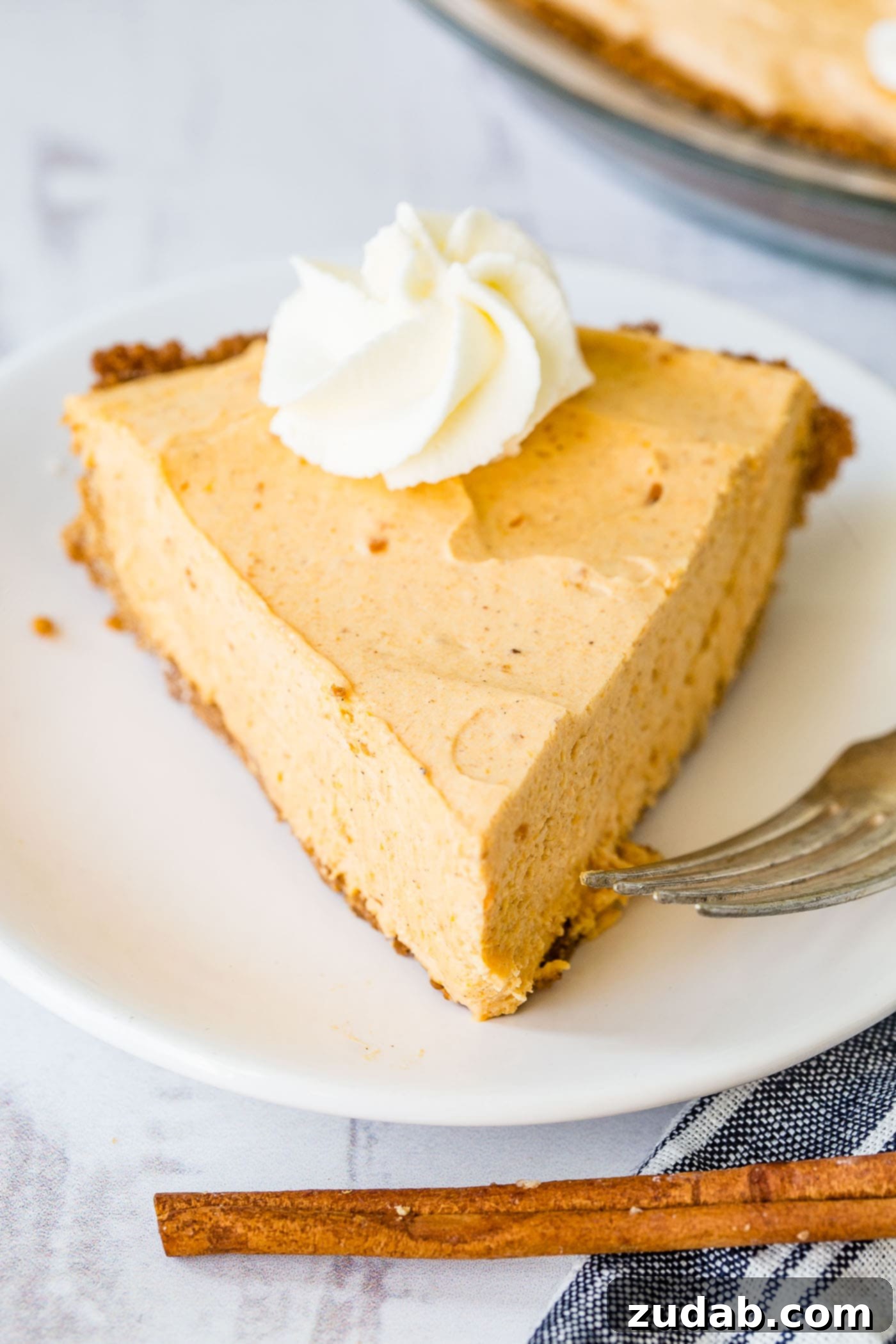 Marshmallow No Bake Pumpkin Pie A photo of a slice of no bake pumpkin pie with a swirl of whipped cream on top, ready to be enjoyed.
