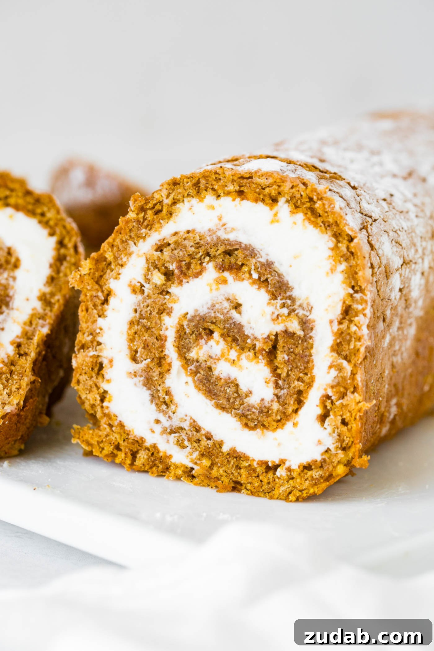 Better Than Libby's Pumpkin Roll Recipe A photo of a cross-section of a pumpkin roll showcasing the generous cream cheese filling.