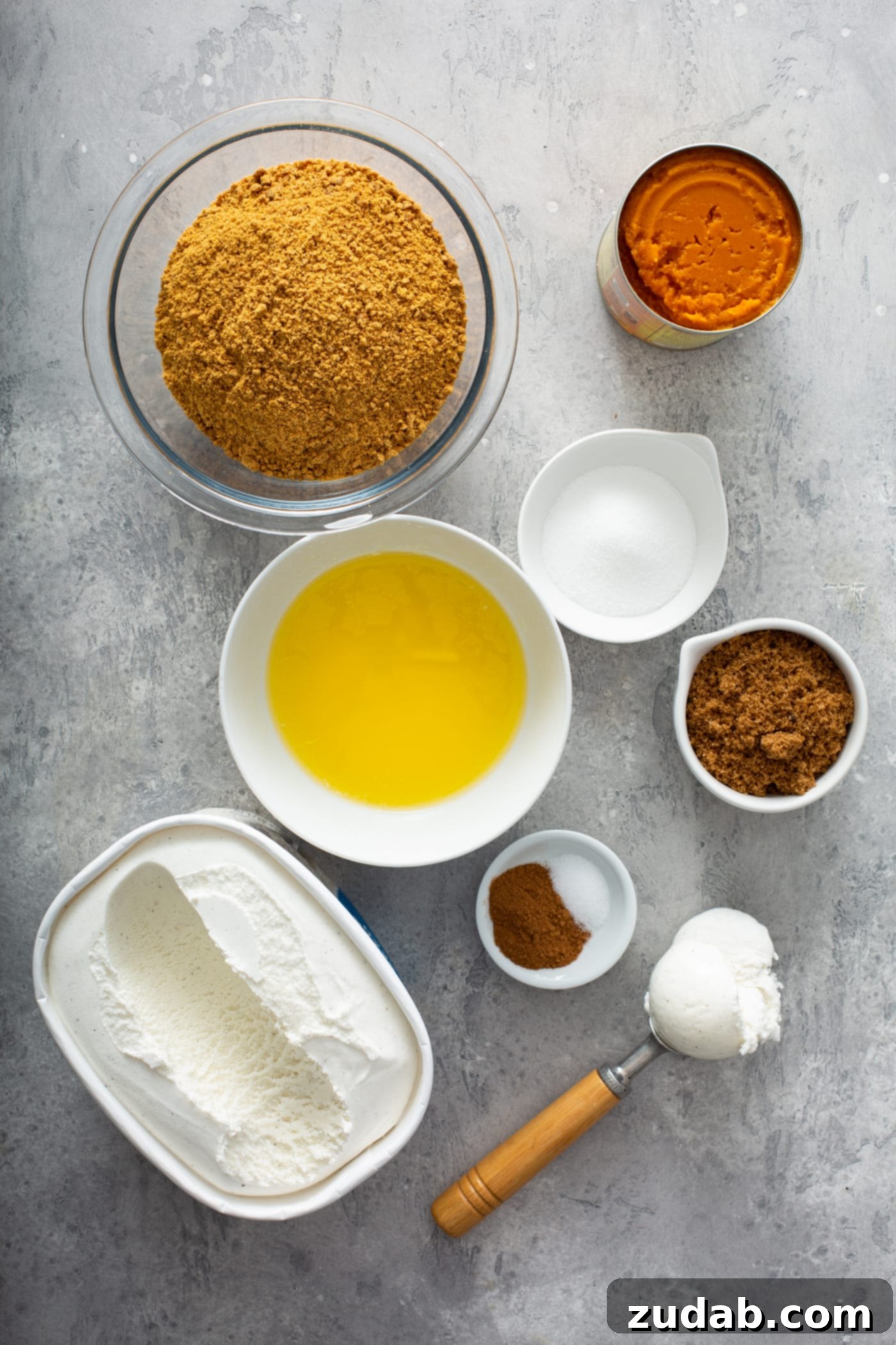 A delightful arrangement of small containers showcasing the essential ingredients for a pumpkin ice cream pie. Visible are containers of pumpkin puree, crushed gingersnap crumbs, melted butter, aromatic spices, granulated sugar, rich brown sugar, and creamy vanilla ice cream, all ready for creation.