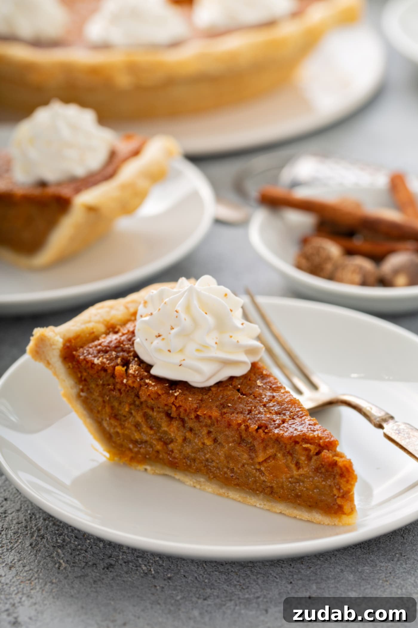 Perfectly Southern Sweet Potato Pie A photo of a slice of sweet potato pie with a dollop of whipped cream on top sitting on a white plate.