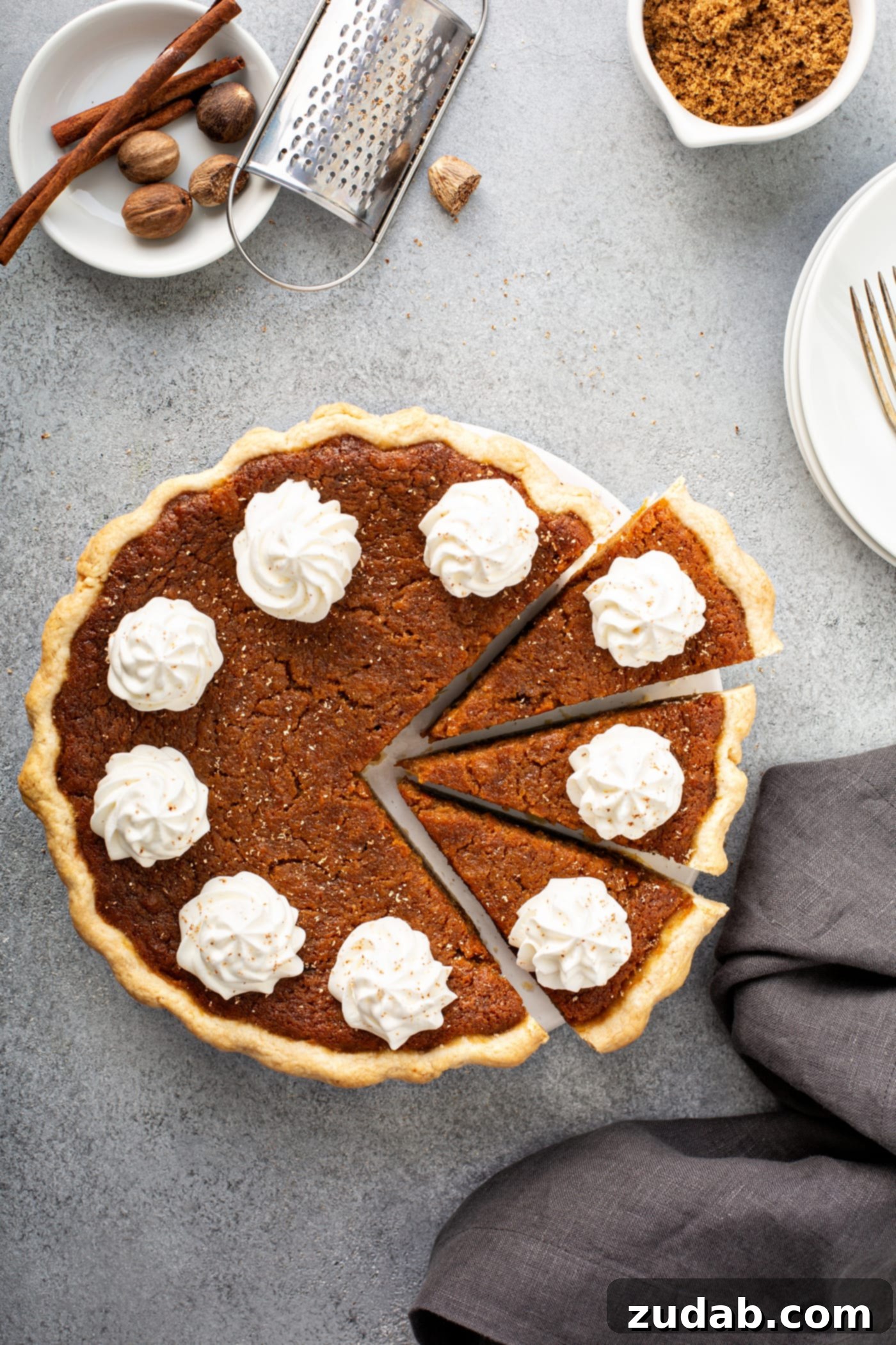 Perfectly Southern Sweet Potato Pie A photo of a baked sweet potato pie covered in dollops of whipped cream with three slices pulled out.