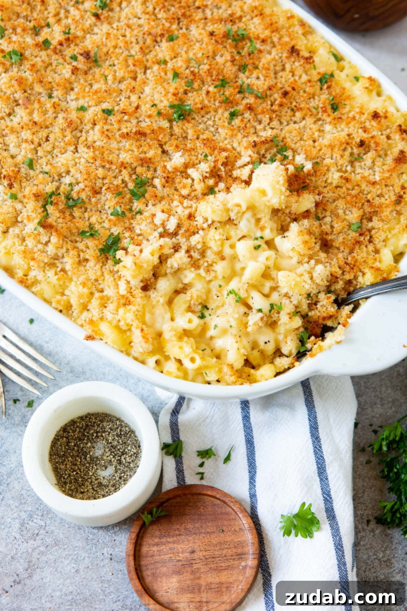 Best Macaroni and Cheese Ever Baked Macaroni and cheese in a casserole dish, topped with browned bread crumbs. A fork and a container of pepper are next to the dish.