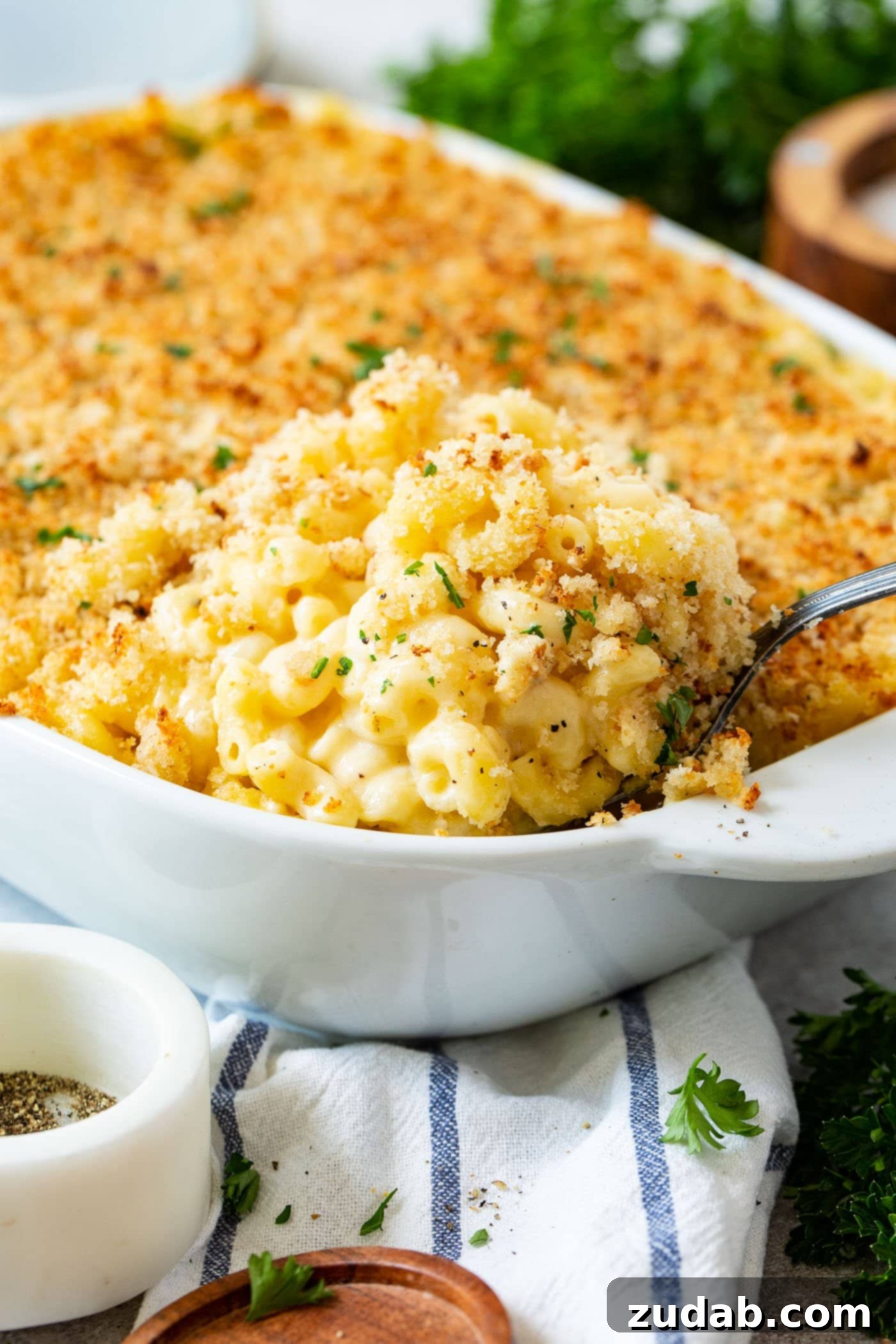 Best Macaroni and Cheese Ever A casserole dish filled with baked mac and cheese, topped with crispy bread crumbs and a serving spoon.